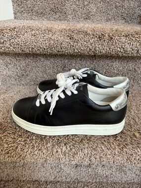 Jimmy Choo Women’s Black Leather Low-Top Sneakers with Silver Heel Accent.